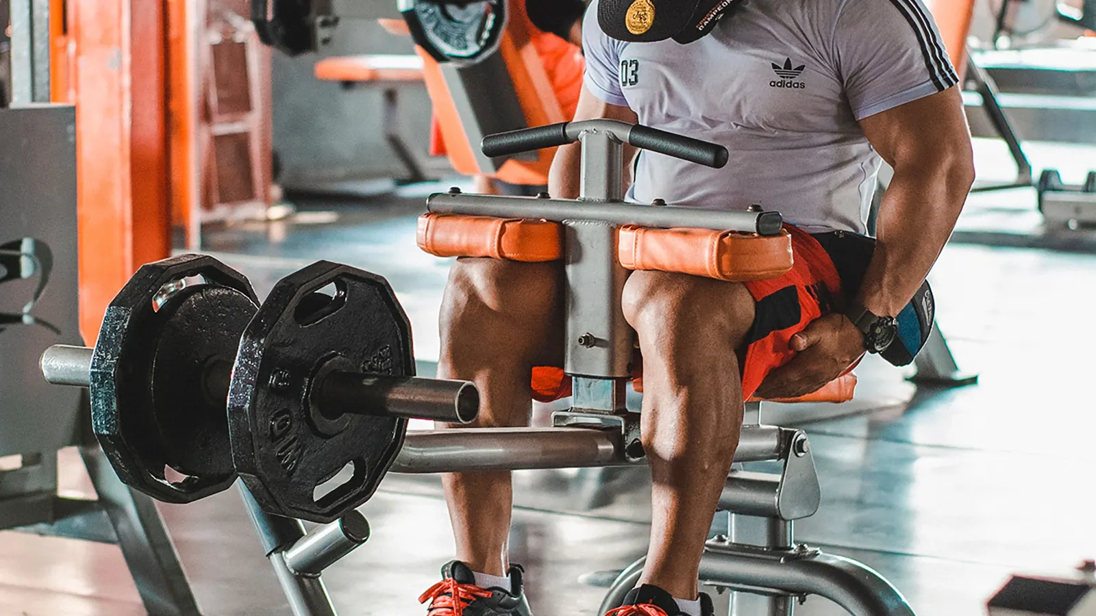 Man performing a seated calf raise in a gym